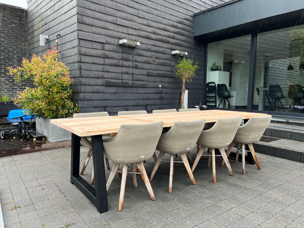 Douglas tuintafel Olena met stalen poten en aangeschoven stoelen, geplaatst naast een schuifpui